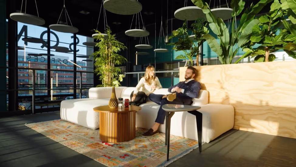Twee adviseurs in gesprek in een lichte lounge met planten en designmeubilair